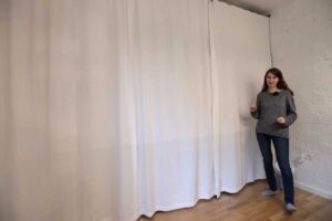 Závěs přes celou stěnu garsonky zakrývající rozsáhlou vestavěnou šatnu.