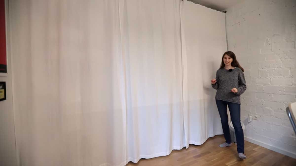 Závěs přes celou stěnu garsonky zakrývající rozsáhlou vestavěnou šatnu.