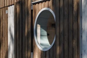 Detail kruhového okna v dřevěné fasádě šumavské chalupy