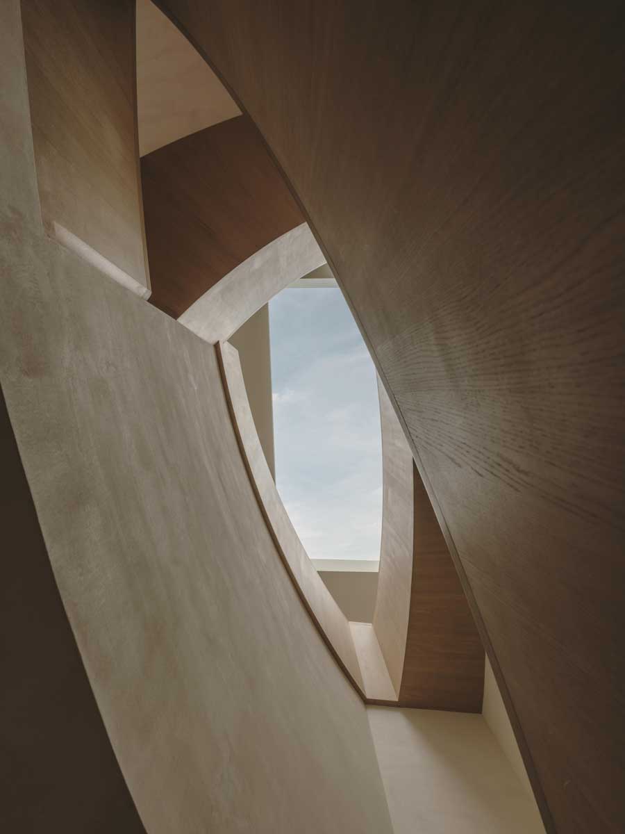 Detail atypicky tvarovaných stěn a průhledů se světlíkem v interiéru rodinného domu