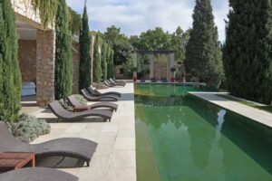 Venkovní bazén u historického sídla Brigitte Bardot obklopený cypřiši a lehátky na Francouzské riviéře