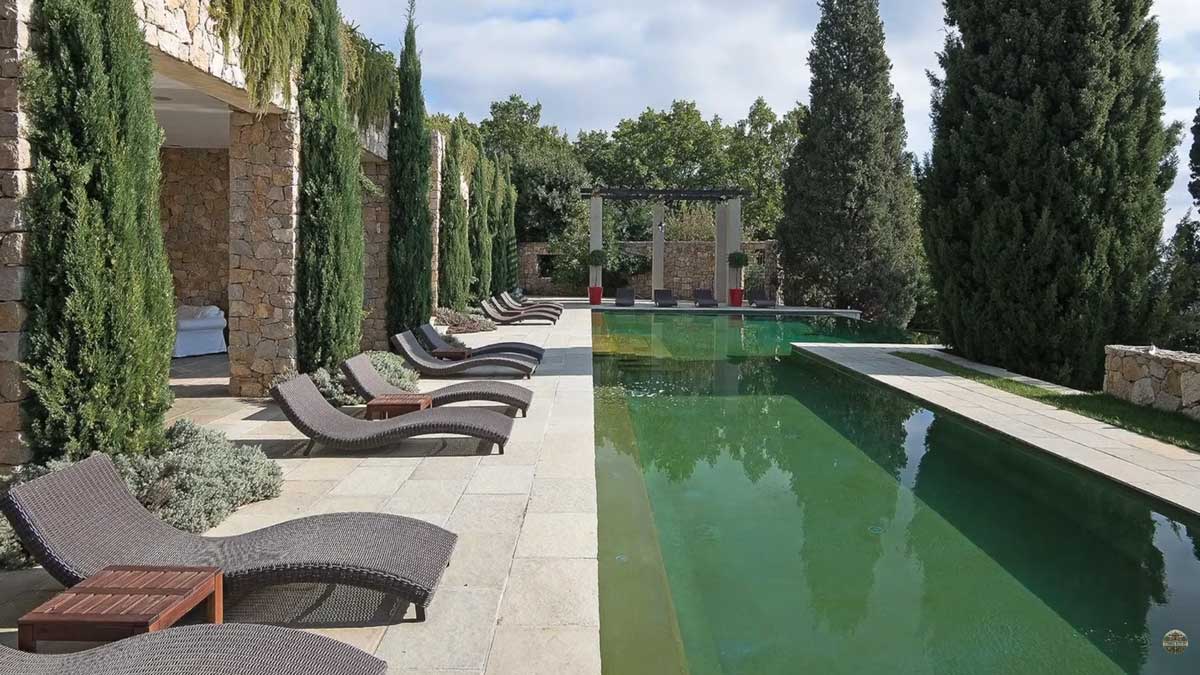 Venkovní bazén u historického sídla Brigitte Bardot obklopený cypřiši a lehátky na Francouzské riviéře