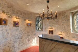 Kamenná chodba historického sídla Brigitte Bardot na Francouzské riviéře s původními kamennými zdmi a intimním osvětlením