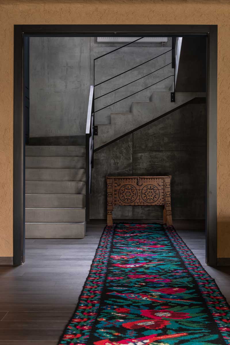 Betonové schodiště v domě Ridnyj kombinující surový beton, dřevo a kovové prvky