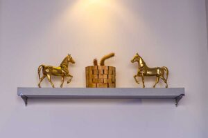 Zlaté dekorativní sošky bez praktické funkce umístěné na minimalistické polici