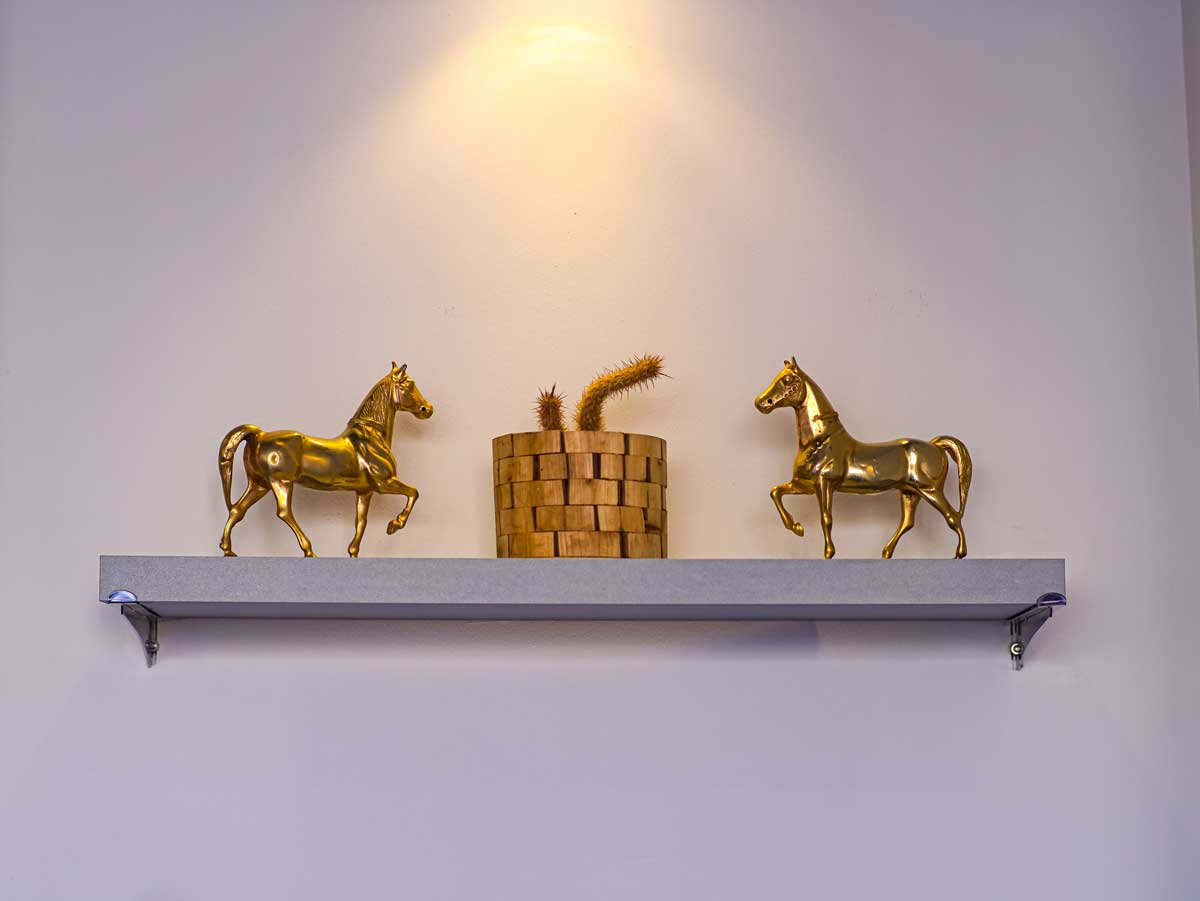 Zlaté dekorativní sošky bez praktické funkce umístěné na minimalistické polici