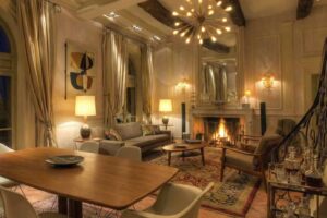 Elegantní obývací pokoj v domě Brigitte Bardot s krbem, historickými prvky a teplým osvětlením