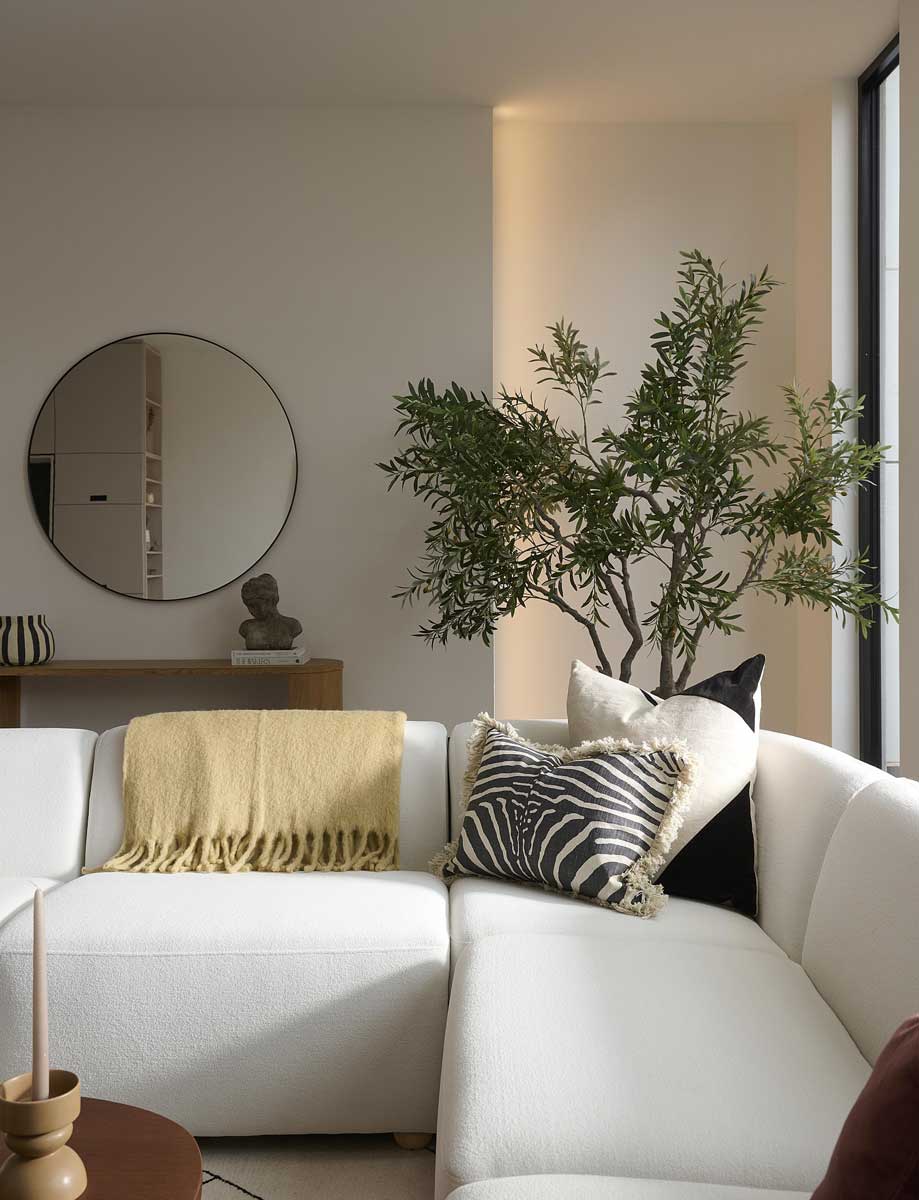 Detail pohovky v obývacím pokoji s dekorativními polštáři