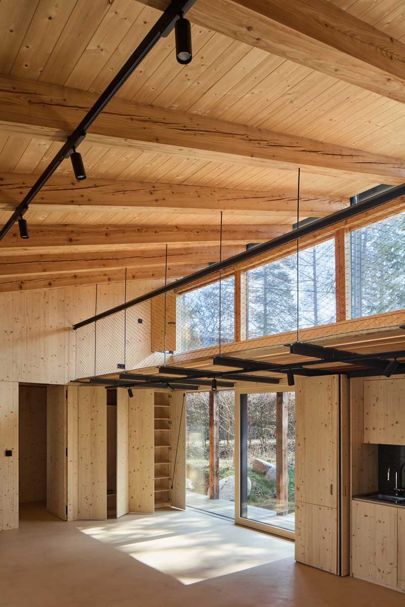 Otevřená denní zóna přístavby na Medníku s vestavěnými úložnými prostory a dřevěným interiérem