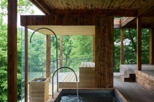 Domácí koupací kout v dřevěné přístavbě domu na Medníku propojený s terasou a lesem