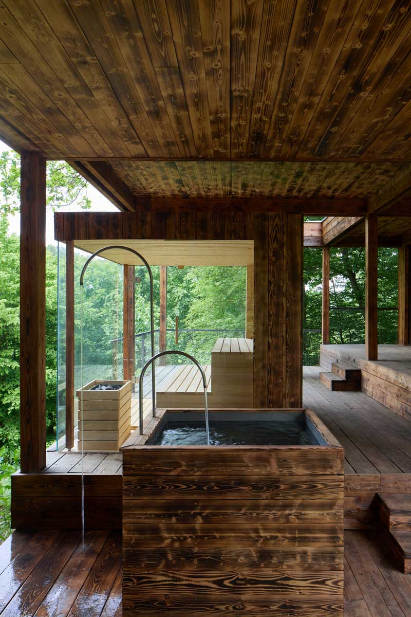 Domácí koupací kout v dřevěné přístavbě domu na Medníku propojený s terasou a lesem