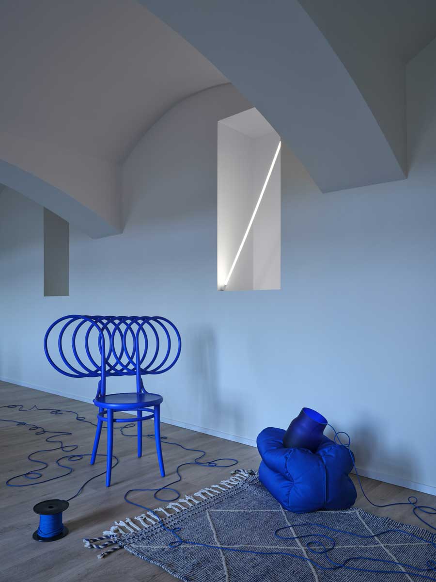 Interiér bytu s obloukovým stropem a výrazným barevným nábytkem v historickém domě po rekonstrukci