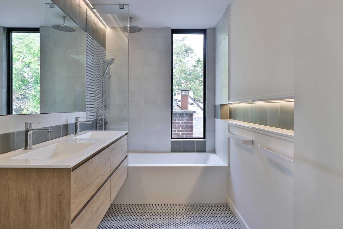 Druhá koupelna s vanou, umyvadlovou skříňkou a velkým oknem