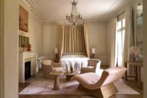 Ložnice s posezením, křesly a jemnými textiliemi v neutrálních tónech