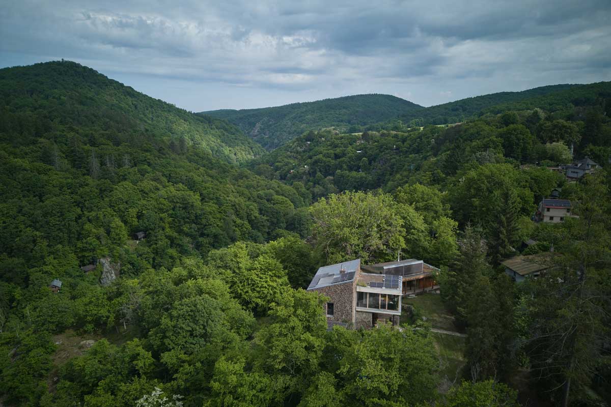 Přístavba domu na Medníku zasazená mezi stromy v prudkém svahu nad údolím.