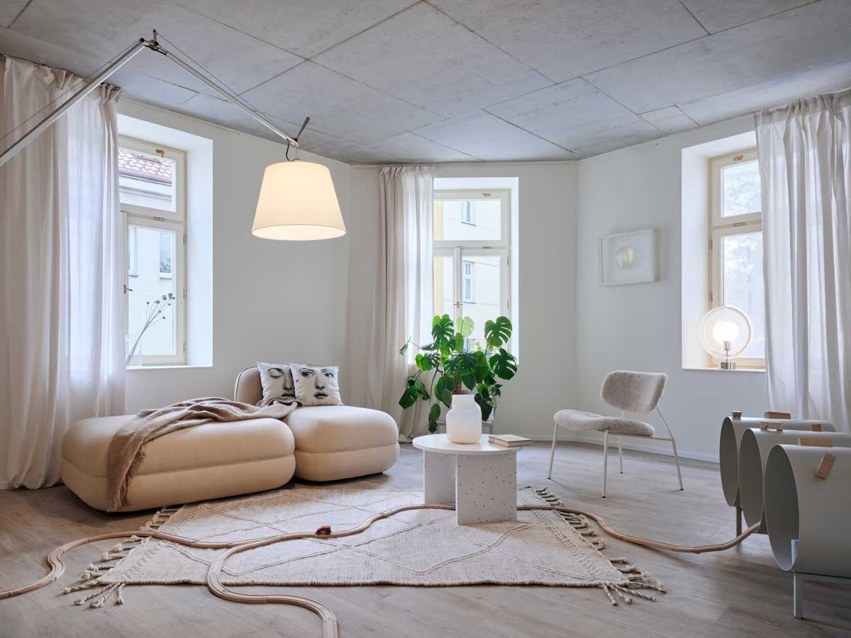 Obývací prostor v bytě s odhaleným betonovým stropem a důrazem na jednoduchost a klidnou atmosféru