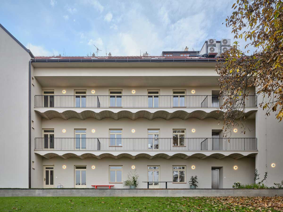 Pohled do vnitrobloku rekonstruovaného pavlačového domu s nově pojatými pavlačemi a světlou fasádou