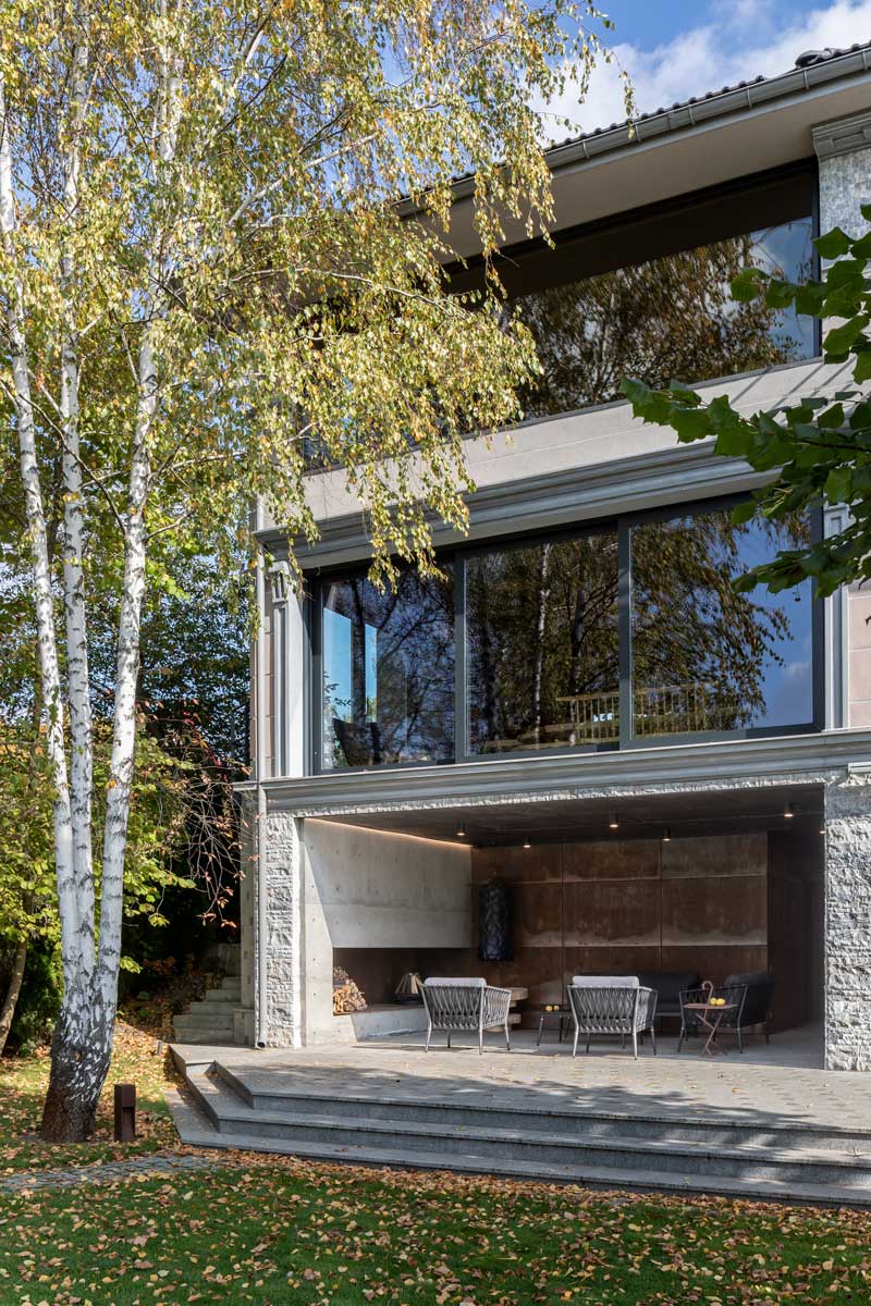 Exteriér domu Ridnyj zasazený do svahu s výhledem do zahrady a krajiny