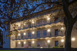 Večerní pohled na rekonstruovaný pavlačový dům s osvětlenými pavlačemi a klidnou atmosférou vnitrobloku