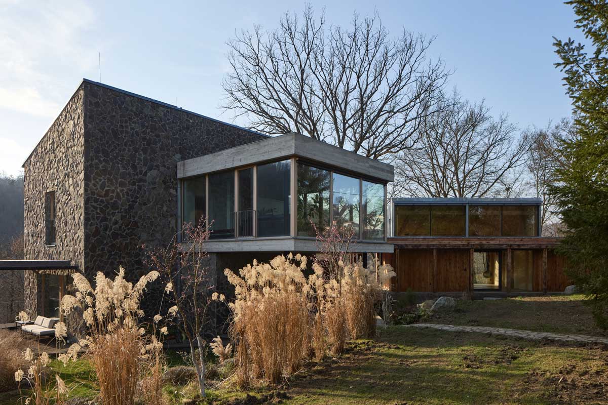 Kamenná fasáda původního domu v kontrastu s lehkou dřevěnou přístavbou