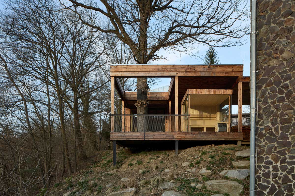 Přístavba Domu Medník umístěná na okraji lesa mezi stromy