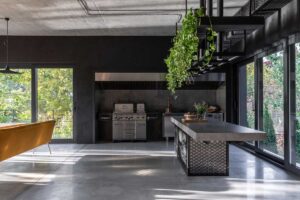 Grilovací kuchyně v domě Ridnyj s betonovým ostrůvkem, nerezí a popínavými rostlinami