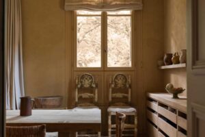 Jídelna s masivním dřevěným stolem, jednoduchým nábytkem a přirozeným světlem