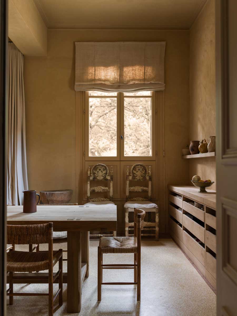 Jídelna s masivním dřevěným stolem, jednoduchým nábytkem a přirozeným světlem