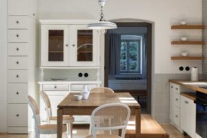 Jídelní kout v chalupě s dubovým stolem světlým nábytkem a historickou vitrínou