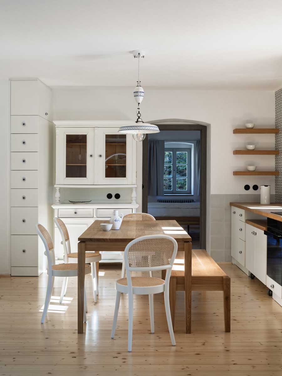 Jídelní kout v chalupě s dubovým stolem světlým nábytkem a historickou vitrínou