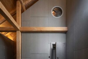 Interiér stodoly s přiznanými dřevěnými trámy a moderní vestavbou z vláknocementových desek