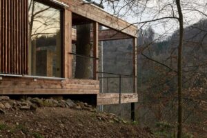 Dřevěná přístavba Domu Medník stojící na ocelové konstrukci ve svahu