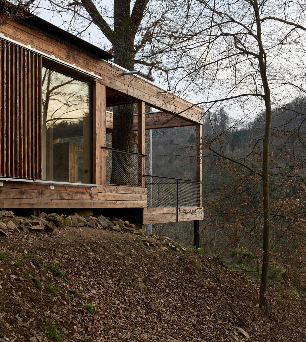 Dřevěná přístavba Domu Medník stojící na ocelové konstrukci ve svahu