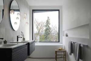 Moderní koupelna s volně stojící vanou, černou umyvadlovou skříňkou a velkým oknem