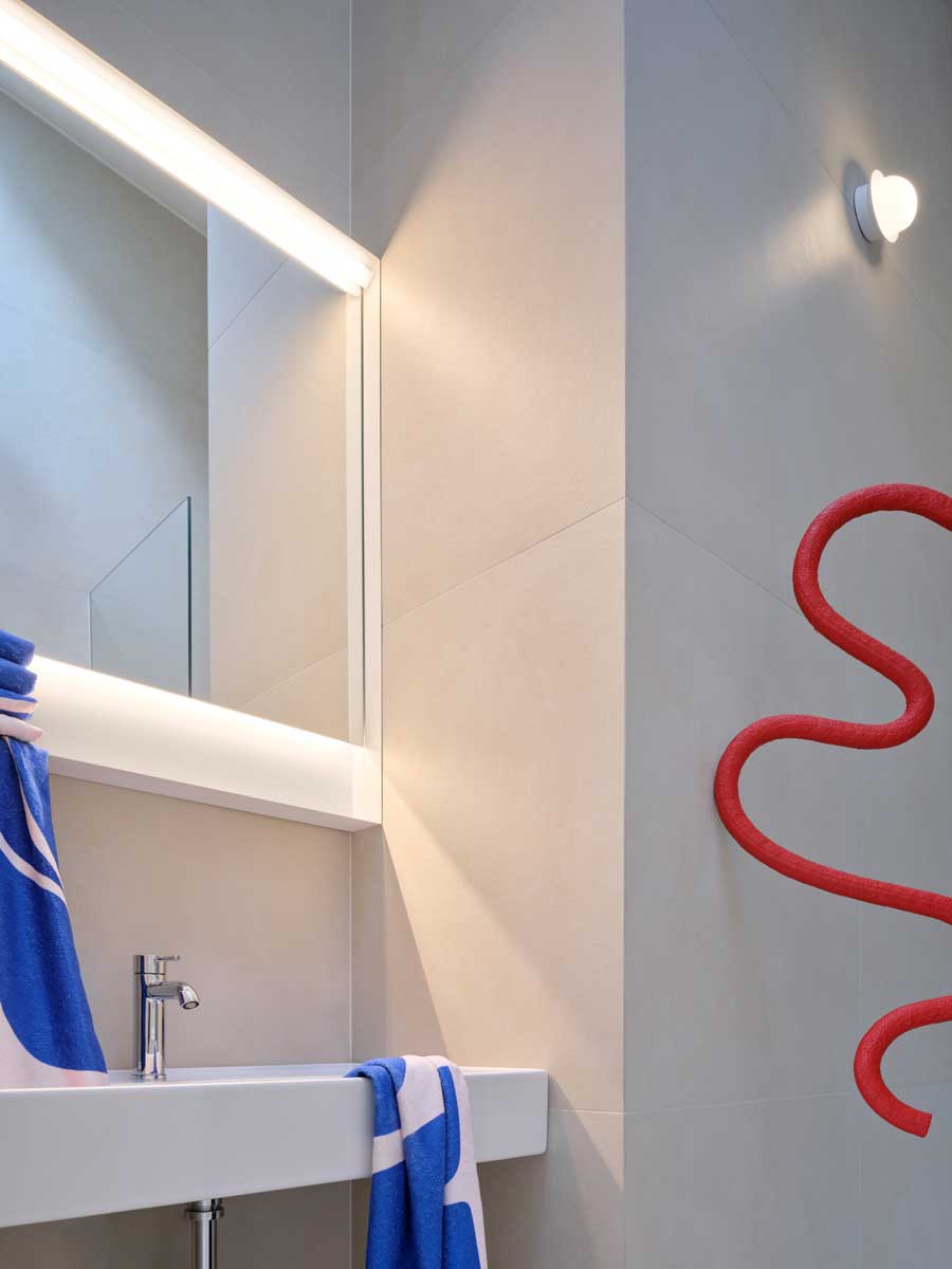 Moderní koupelna v pavlačovém domě s čistými liniemi výrazným barevným detailem a důrazem na funkčnost