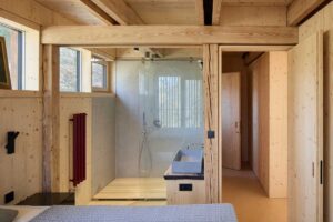 Koupelna v přístavbě Domu Medník s dřevěnými povrchy a skleněnou zástěnou