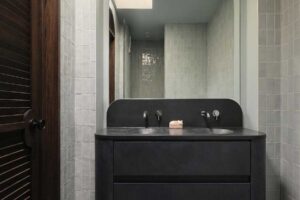 Moderní koupelna s dvojitým umyvadlem, tmavým nábytkem a dekorativní dlažbou