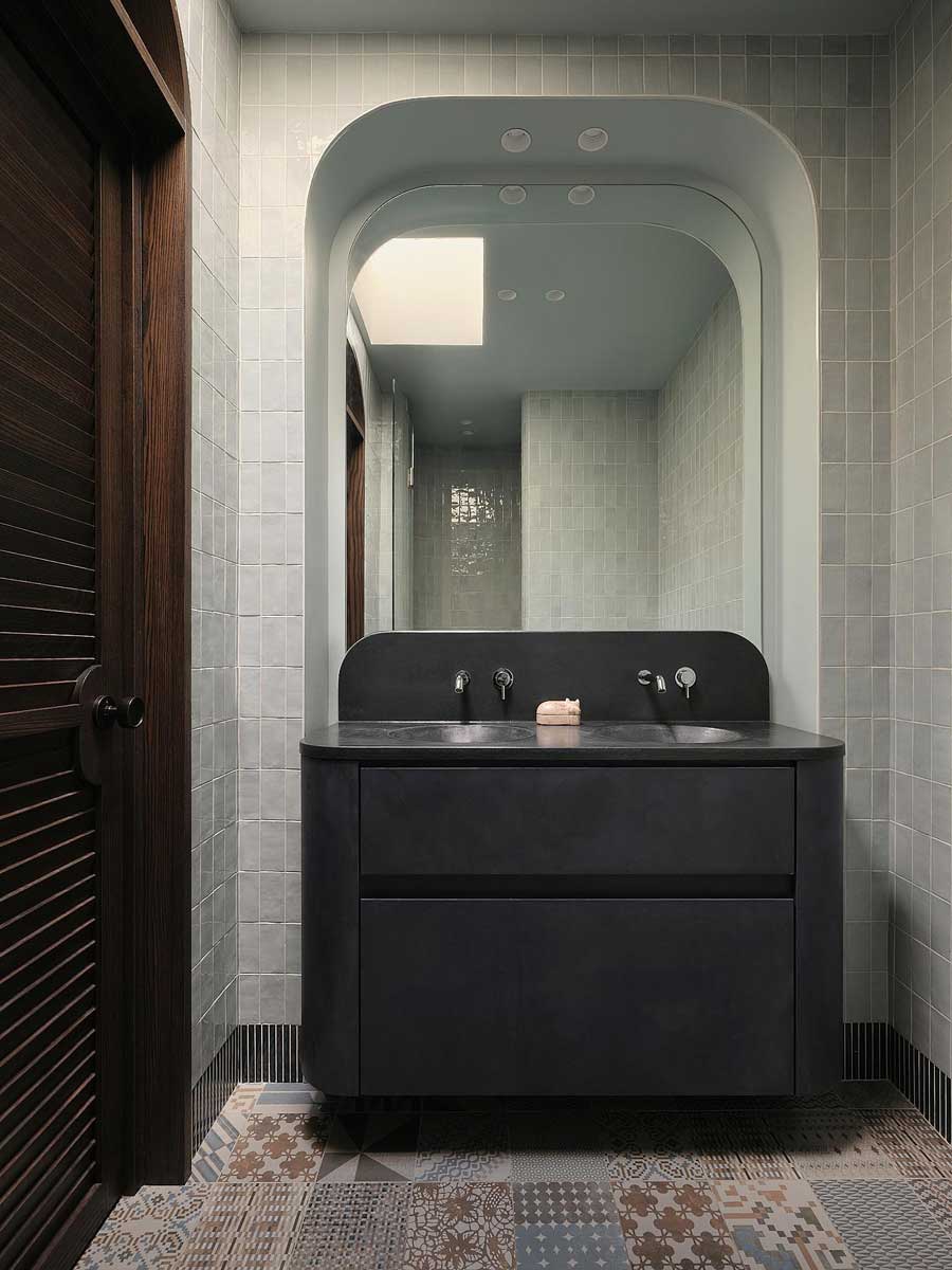 Moderní koupelna s dvojitým umyvadlem, tmavým nábytkem a dekorativní dlažbou