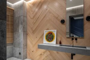 Koupelna s betonem, dřevěným obkladem a minimalistickým umyvadlem