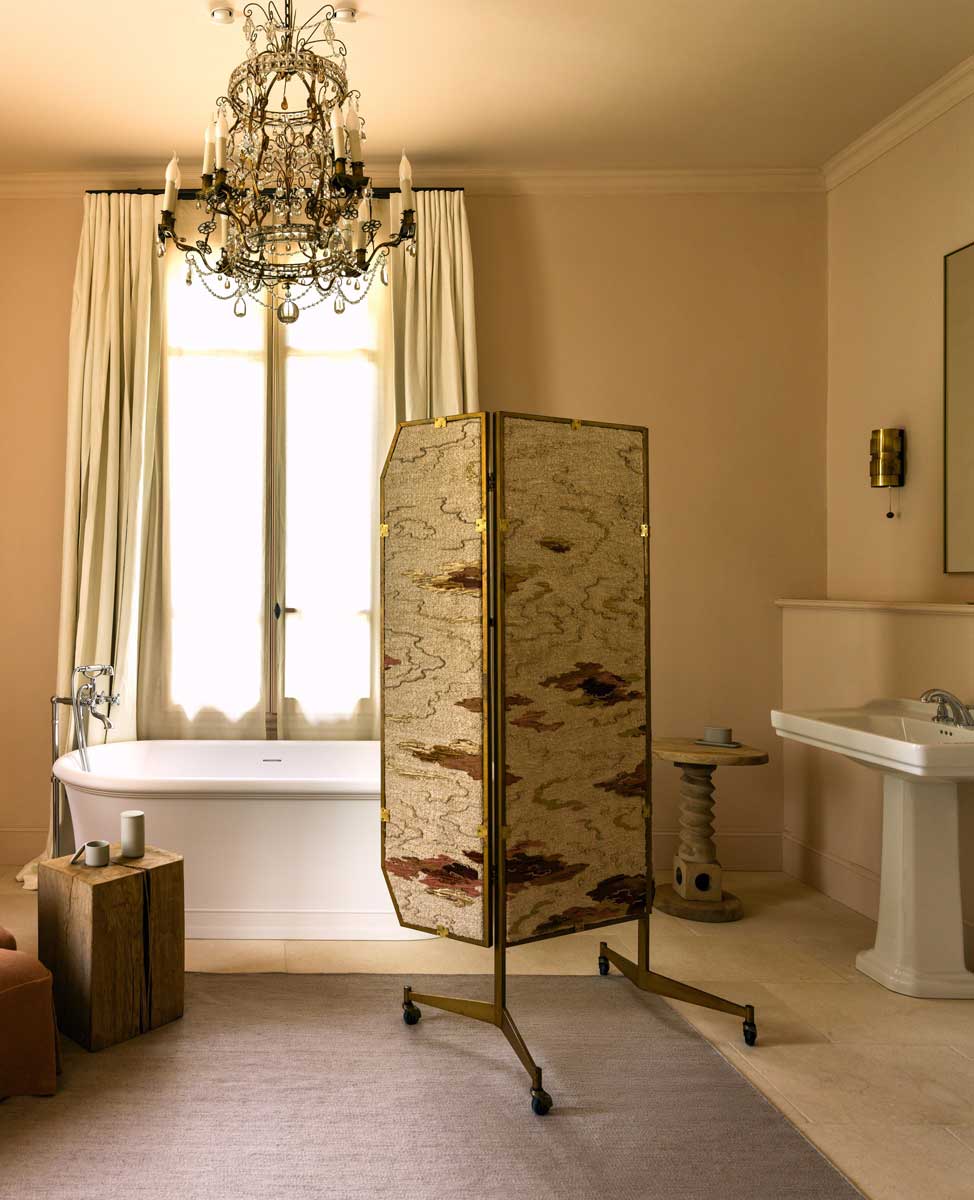 Elegantní koupelna s volně stojící vanou, historickým lustrem a textilním paravánem