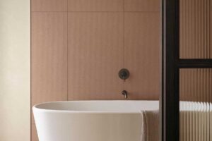 Volně stojící vana v moderní koupelně rekonstruovaného rodinného domu s jemnou barevností a oblými liniemi