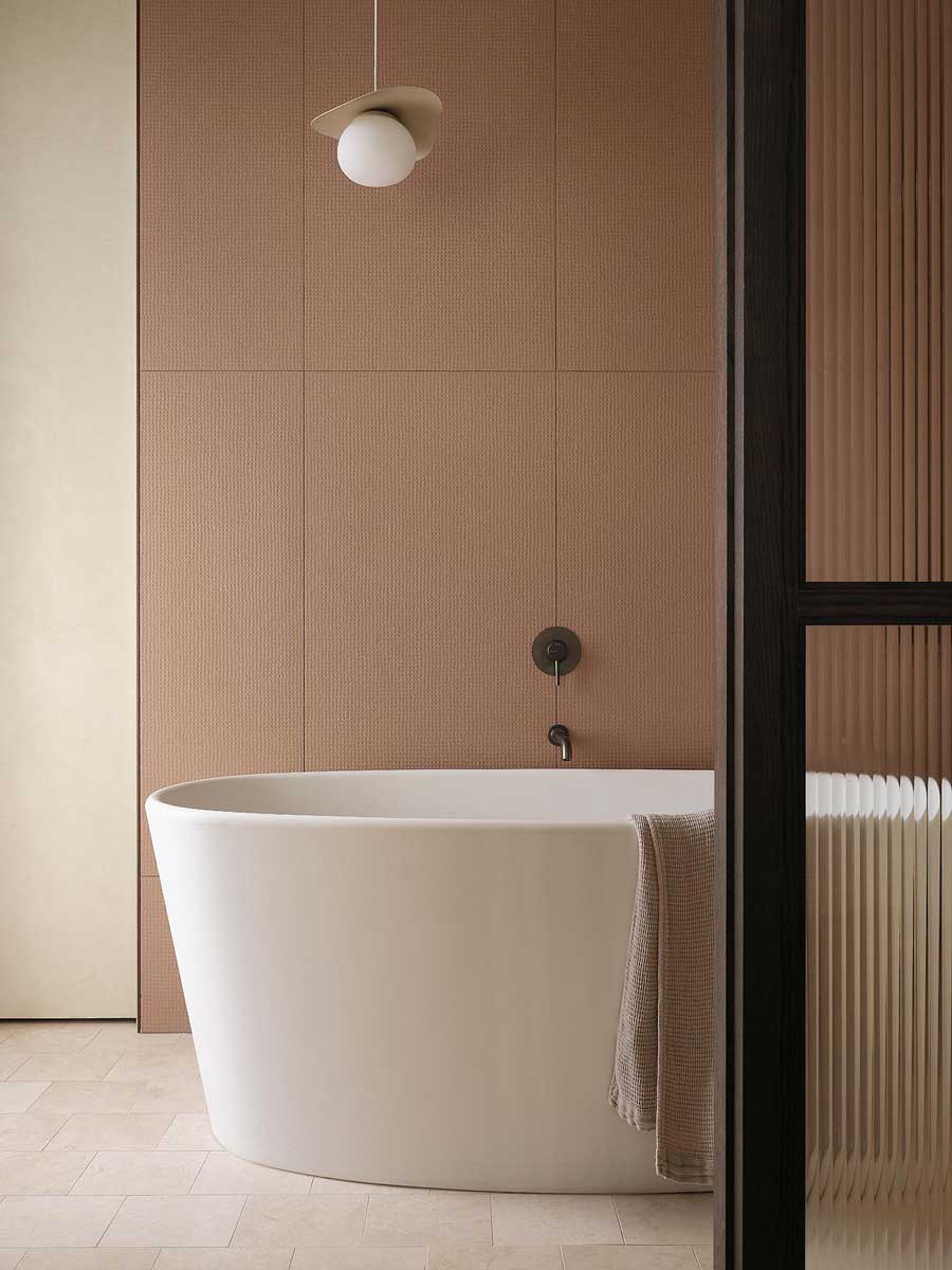 Volně stojící vana v moderní koupelně rekonstruovaného rodinného domu s jemnou barevností a oblými liniemi