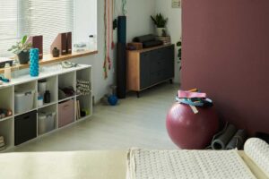 Domácí cvičební kout s podložkou, válcem a drobným fitness vybavením u okna