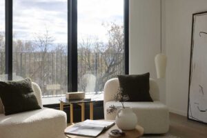 Obývací kout s křesly u velkého okna a výhledem do zahrady