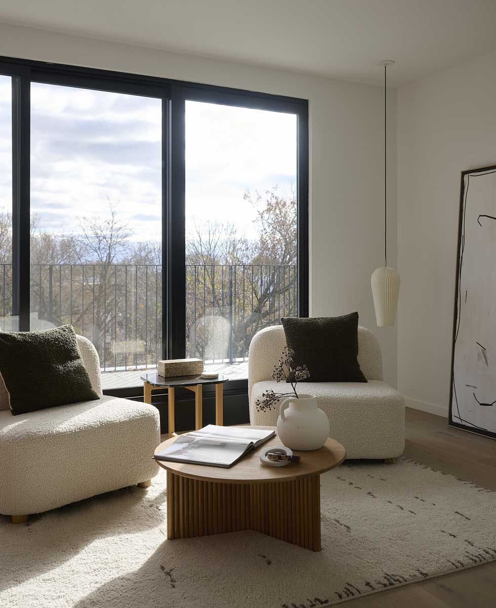 Obývací kout s křesly u velkého okna a výhledem do zahrady