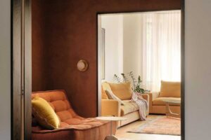 Relaxační křeslo v obytné části domu s teplými barvami, textiliemi a měkkým světlem