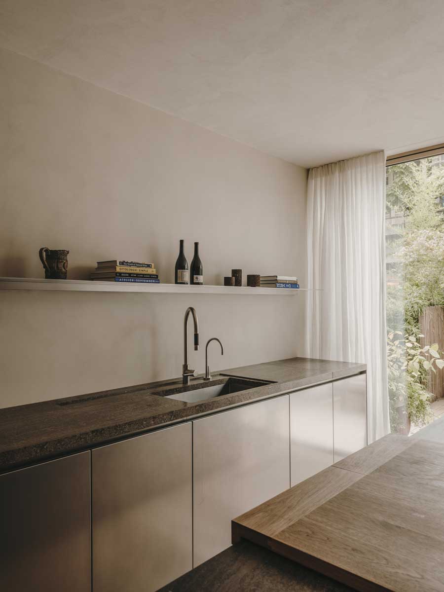 Kuchyně s kamennou pracovní deskou a vestavěnými spotřebiči v klidném minimalistickém interiéru