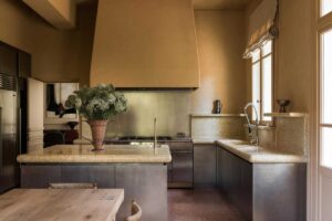 Kuchyně s kamennou pracovní deskou, ostrůvkem a tlumenými přírodními barvami