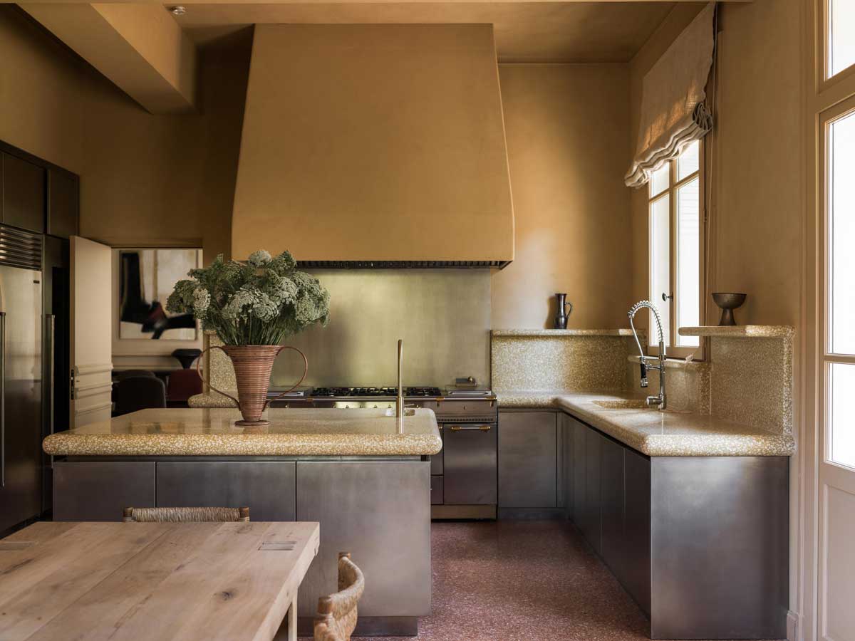 Kuchyně s kamennou pracovní deskou, ostrůvkem a tlumenými přírodními barvami