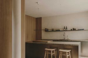 Kuchyně s ostrůvkem z přírodních materiálů propojená s obytným prostorem rodinného domu